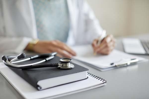 Doctor reviewing medical paperwork and patient records during a health insurance assessment.