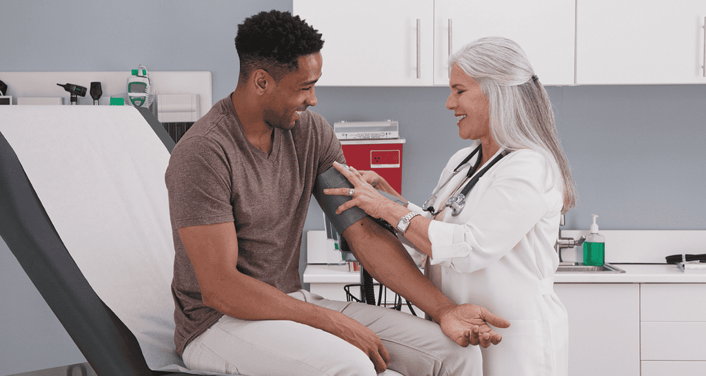 Doctor checking a pilot’s blood pressure during a medical consultation at a clinic.